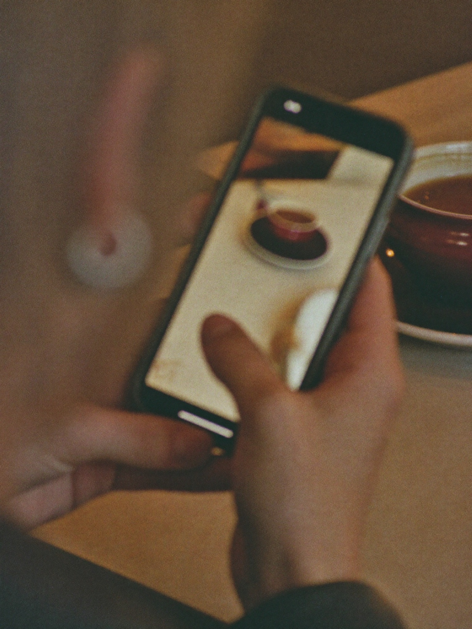 A hand holding a phone mid-conversation at a café table