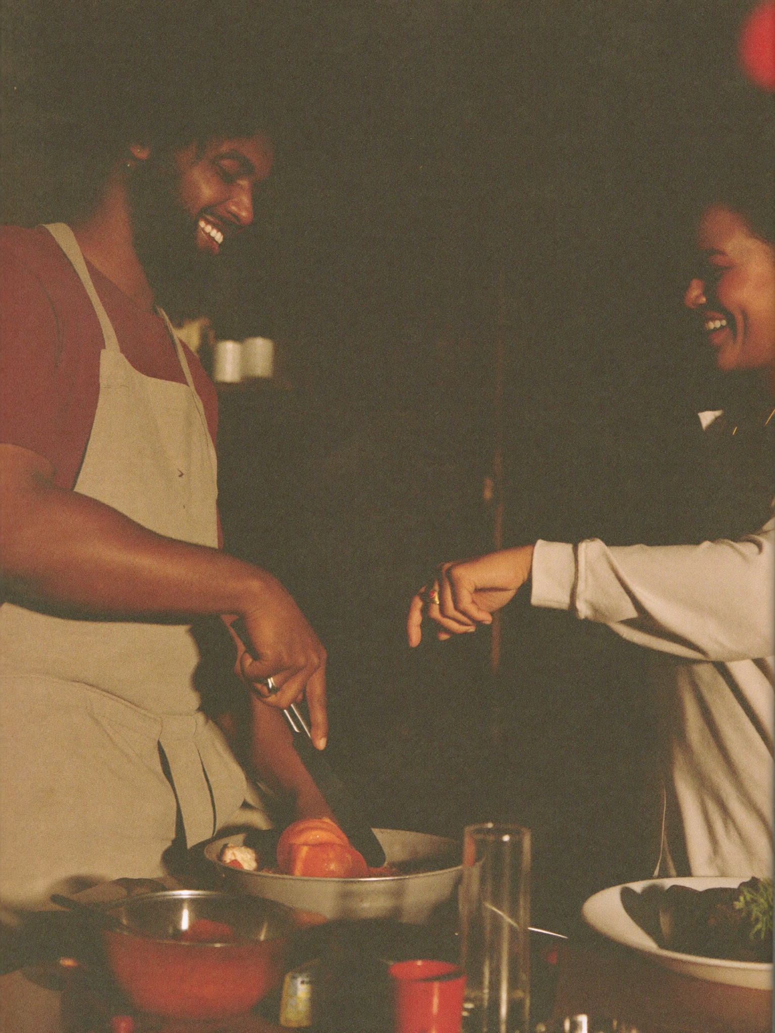A couple laughing while cooking dinner together