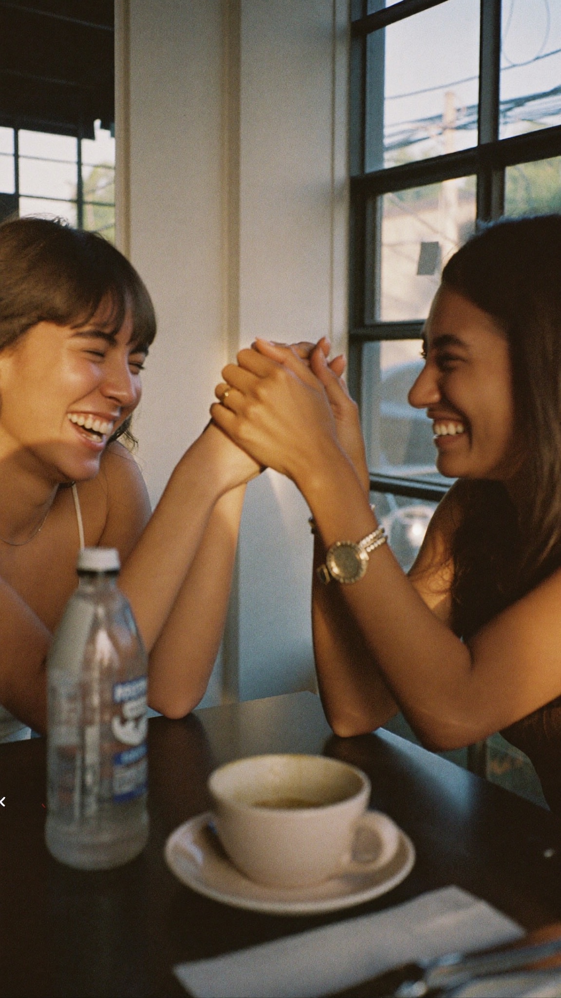 Two friends laughing together over coffee